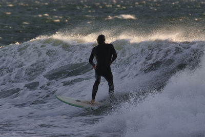 Rear view of man surfing in sea