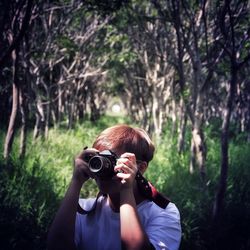 Portrait of woman photographing in forest