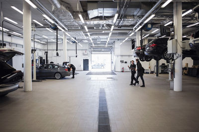 Female mechanic walking with client in auto repair shop