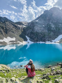 Man sitting by lake against mountains