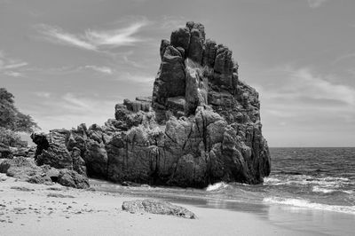 Rock formation on beach against sky