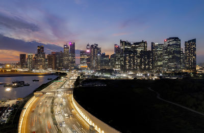 Illuminated city by buildings against sky at night