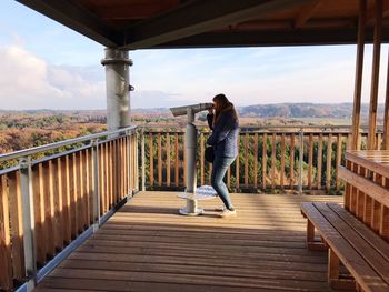 Side view of woman using coin-operated binoculars 