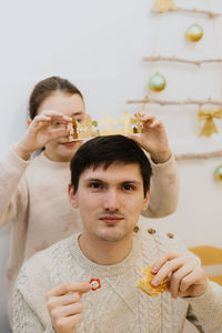 A girl puts a crown on an adult guy who ate a royal galette.