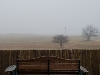 Fence by trees against sky