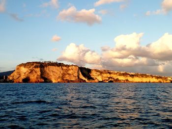 Rock formations by sea against sky