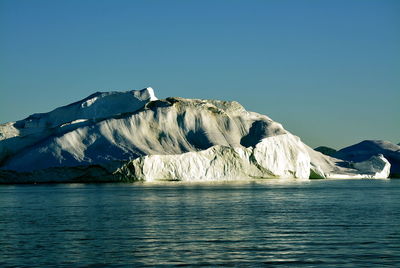 View of majestic iceberg in sea against sky