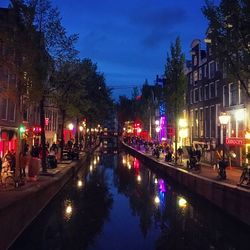 People on illuminated street amidst buildings at night