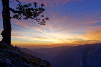 Scenic view of silhouette mountains against orange sky