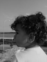 Close-up of cute boy at beach against sky