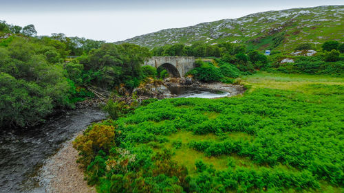 Arch bridge over stream against sky