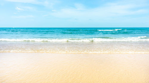 Scenic view of brown sand beach  on blue sea against sky