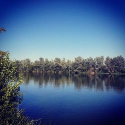 Scenic view of calm lake against clear blue sky