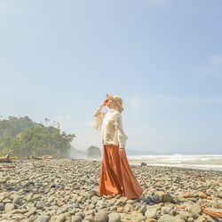 Woman standing at beach against sky