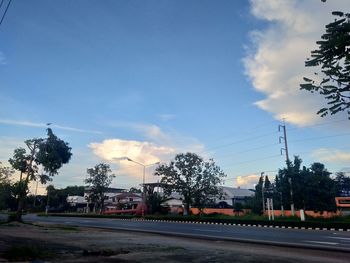 Road by trees against blue sky