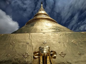 Low angle view of buddha statue against sky