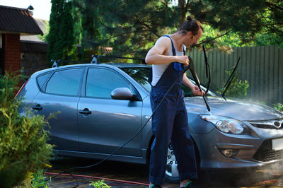 Side view of man with car on road