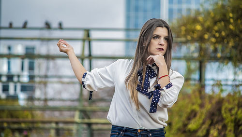 Portrait of young woman standing against building