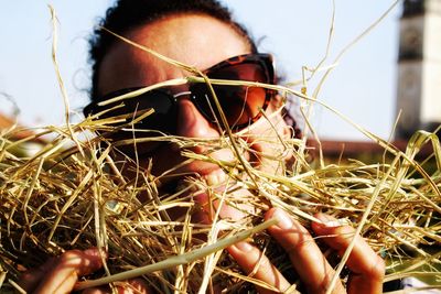 Close-up of man holding plant on field