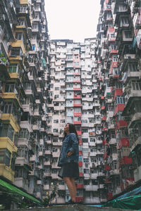 Rear view of woman standing against buildings in city