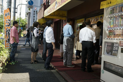 Rear view of people walking on street in city