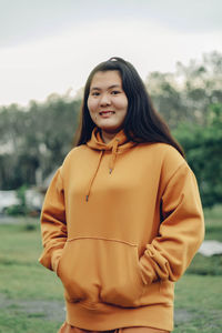 Portrait of young woman standing against trees
