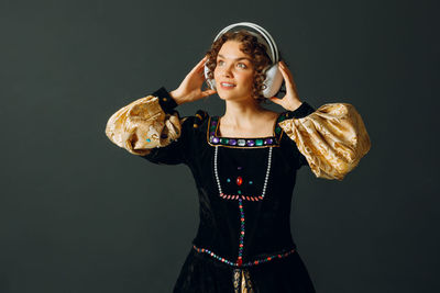 Portrait of young woman standing against black background