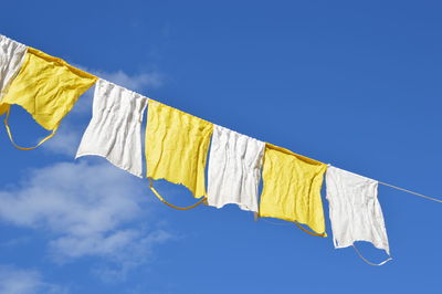 Low angle view of rags against blue sky