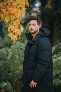 Full length of young man standing by autumn leaves