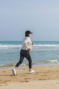 Rear view of man on beach against sky