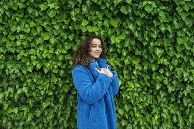 Young woman looking down while standing amidst plants