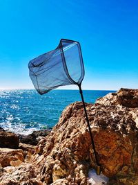 View of rock on beach against blue sky