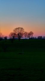 Scenic view of grassy field against sky at sunset