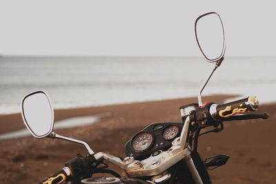 Close-up of bicycle by sea against sky