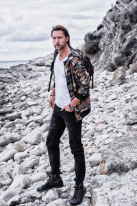 Full length portrait of young man standing on rock