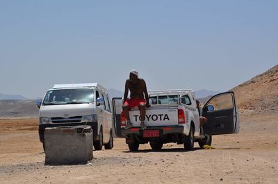 Rear view of woman standing by car against clear sky