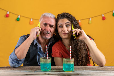 Father and daughter are talking on the smartphone sitting close to each other - studio shot