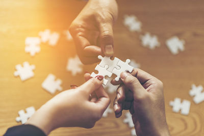 Midsection of business people playing with jigsaw puzzle on table