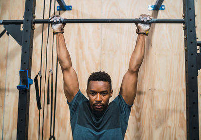 Male athlete hanging from pull-up bar in gym