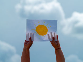 Low section of person holding umbrella against sky