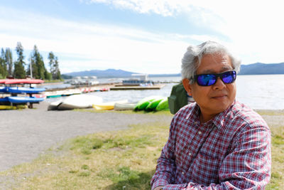 Portrait of man wearing sunglasses at beach against sky