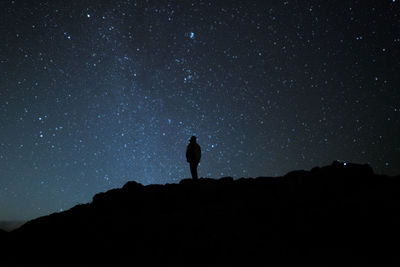 Silhouette man standing against star field at night