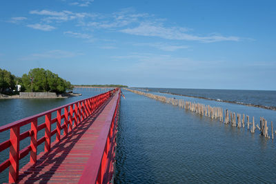 Panoramic view of wooden posts in sea against sky