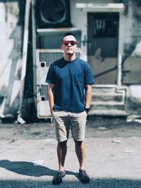 Portrait of young man wearing sunglasses while standing on footpath