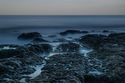 Scenic view of rocks in sea against sky