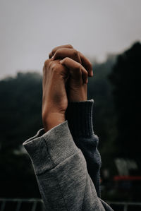 Cropped hands of people holding hands against sky