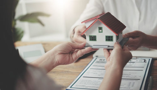 Cropped image of man holding house at home