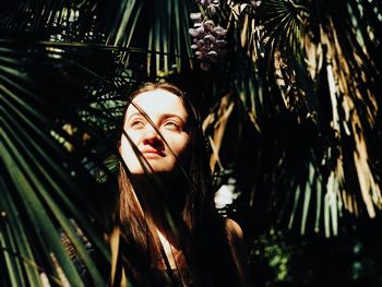 Portrait of young woman with palm tree