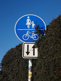 Low angle view of road sign against clear blue sky