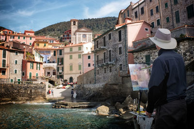 Rear view of artist painting against houses